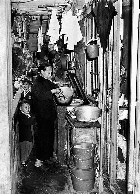 A resettlement block resident cooking in the public corridor.