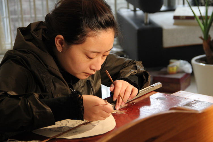 Gong Qian, the bearer of the fifth generation, is demonstrating her skills of making Gong Fan.